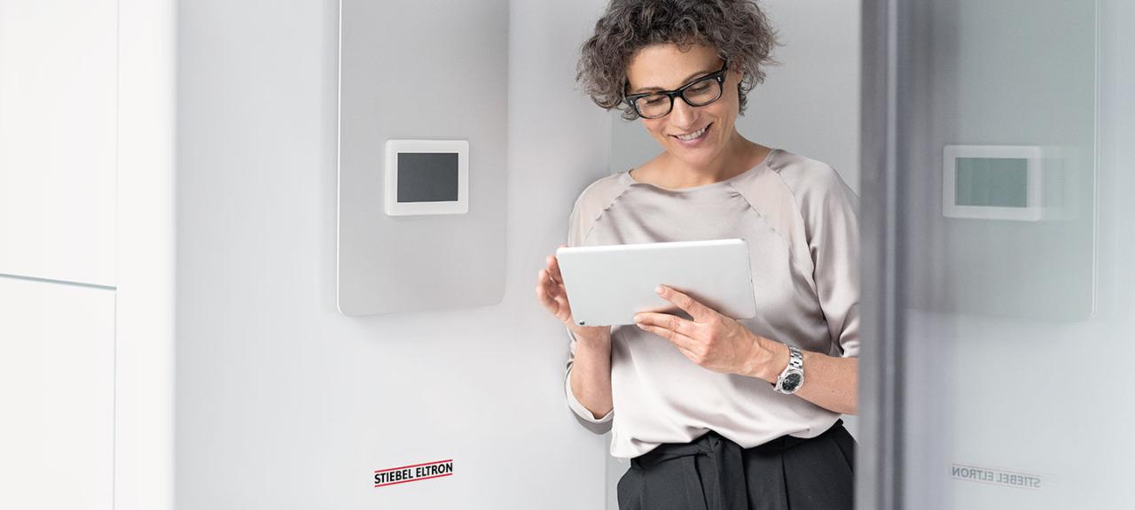 Frau mit Tablet neben einer Heizungsanlage von STIEBEL ELTRON